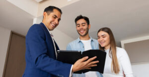 Corretor apresentando contrato a um casal, ilustrando contabilidade imobiliária do básico para locações, vendas e impostos sem dor de cabeça.