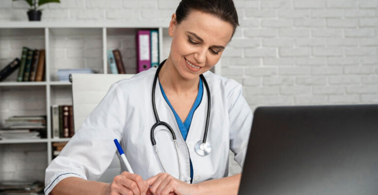 Médica analisando documentos no computador, ilustrando equiparação hospitalar sua clínica e a possibilidade de reduzir impostos de forma legal.